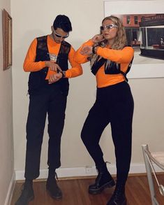 two people dressed in orange and black standing next to each other on a wooden floor