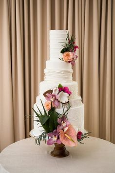 a three tiered cake with flowers on the top and bottom is sitting on a table