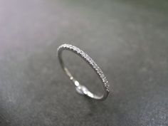 a white gold wedding ring with diamonds on it's sidestrap, sitting on a gray surface