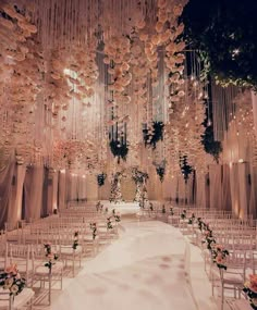 a wedding ceremony setup with white chairs and chandeliers hanging from the ceiling,