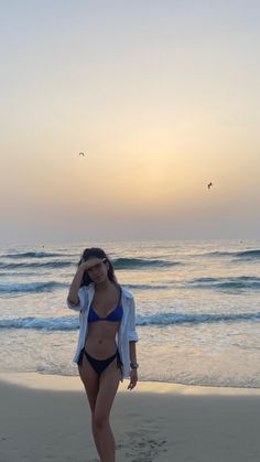 a woman standing on top of a beach next to the ocean