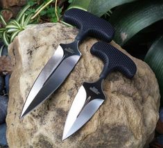 two knives sitting on top of a rock