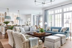 a living room filled with lots of furniture next to two large windowed walls and windows