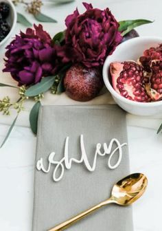 a table topped with flowers and fruit next to a bowl of pomegranate