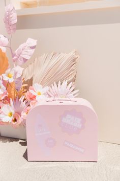 a pink box with flowers in it sitting on the ground