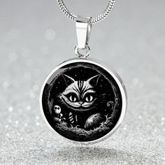 Elevate your Halloween style with our Engraved Cheshire Cat Necklace. This Gold Cat Charm Necklace is the perfect gift for Cat Lovers who adore a touch of the Gothic. Embrace the whimsical and mysterious aura of the Cheshire Cat with this exquisite piece of Gothic Jewelry. ➜ Our patent-pending jewelry is made of high quality surgical steel with a graphic image that's printed directly onto the steel surface with a shatterproof liquid glass coating and includes an 18k gold finish option. There are Black Collectible Necklace For Halloween, Spooky Black Necklace For Gift, Black Engraved Necklace For Halloween, Black Engraved Jewelry For Halloween, Engraved Black Jewelry For Halloween, Collectible Black Stainless Steel Necklace, Halloween Black Cat Design Jewelry, Spooky Black Jewelry Gift, Halloween Engraved Necklace Gift