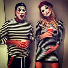 two people with painted faces standing next to each other in front of a wall wearing striped shirts