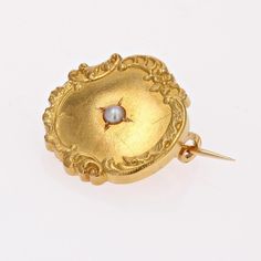 Brooch in 18 karat yellow gold, eagle head hallmark. This round collar brooch in yellow gold is bordered by a floral and arabesque design and features a fine half-pearl in the center. The fastening system is a safety pin. Pearl diameter : 2/2.5 mm approximately. Brooch diameter : 19 mm approximately, thickness : 3 mm approximately. Total weight of the jewel : 2 g approximately. Authentic antique jewel - French work of the 20th Century. Each piece of jewelry is checked and repolished by our Frenc Victorian Baroque Brooches For Formal Occasions, Victorian Baroque Brooch For Formal Occasions, Elegant Yellow Gold Baroque Brooches, Heirloom Cabochon Brooches For Formal Occasions, Heirloom Brooches With Cabochon For Formal Occasions, Elegant Yellow Gold Medallion Brooches, Elegant Medallion Brooch For Formal Occasions, Vintage Gold Brooch With Pearl Pendant, Luxury Gold Brooches With Intricate Design