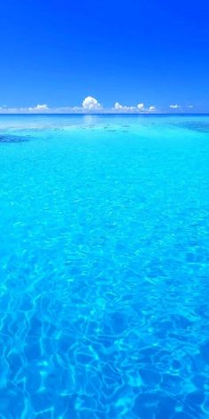 the water is very clear and blue with some clouds in the sky on top of it