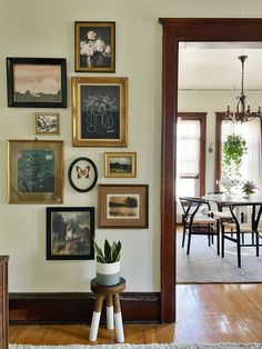 a dining room with pictures on the wall and a potted plant next to it