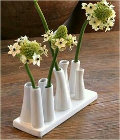 three white vases with flowers in them on a table