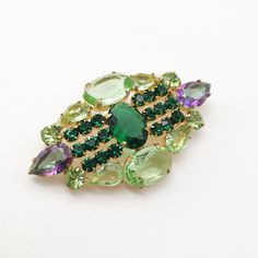 Outstanding glass rhinestone vintage brooch featuring emerald green, grass green, and watermelon open-back stones! Made in Czechoslovakia in the 1960s, it has a beautiful golden color finish. It's in excellent condition, with a perfectly working closure. The brooch is not signed.  Dimensions: 1 1/4" by 2 1/2". Vintage Green Brooch Jewelry, Antique Green Gemstone Brooches, Green Gemstone Wedding Brooches, Retro Green Brooch Jewelry, Art Deco Green Brooches For Wedding, Vintage Green Brooch For Party, Green Art Deco Brooches For Wedding, Mid-century Green Brooch For Formal Occasions, Green Jeweled Brooches As Gift