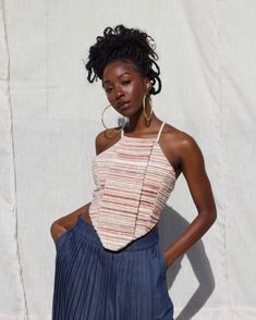 a woman standing in front of a white wall with her hands on her hips and looking at the camera