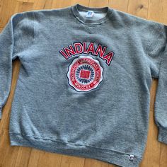 "This piece is a vintage crewneck sweater from the 1990s for Indiana University Bloomington. This grey pullover sweatshirt has a big spell out and crest for the Hoosiers school on the front.  -50% Polyester, 38% Cotton, 12% Rayon -No Major Stains, Yellowing, or Flaws Tag Size: XL *refer to measurements for true fit* Pit to Pit: 23\" Length: 25\" Please also assess the photos and measurements carefully using your own personal judgement as we do not accept returns. Keep in mind that this is a piece of vintage clothing that may hold a residual scent from its past. While we wash all of the clothing we sell (except for certain items which are steam cleaned) we cannot guarantee that we have been able to remove all of the stubborn scents. Buyers should be prepared for the possibility of having to