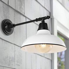 an industrial style light fixture on the side of a building with white brick walls and windows