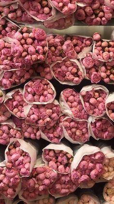 many bags filled with pink and white candy beans are stacked on top of each other