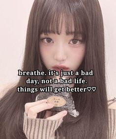 a girl with long brown hair and bangs holding a badge in her hand that says breathe it's just a bad day, not a bad life things will get better vv