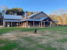 a black dog standing in front of a large house on top of a lush green field