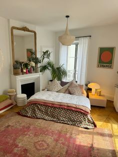 a bedroom with a bed, mirror and fireplace in the corner next to a window