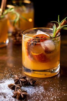 a close up of a drink in a glass with an orange peel on the rim