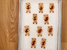 cookies shaped like teddy bears with bacon on them in a cookie sheet, ready to be baked