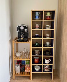 there is a coffee maker and shelves with cups on them in the corner of this room