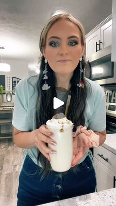 a woman with long hair holding a drink in her hand and looking at the camera