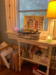 an old record player sits on top of a table in front of a window filled with books and magazines