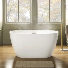 a large white bath tub sitting on top of a wooden floor next to a window