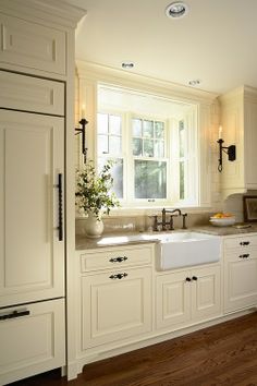 a kitchen with white cabinets and wood flooring next to an open doored window