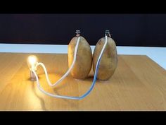 two potatoes sitting on top of a wooden table next to a light that is plugged in