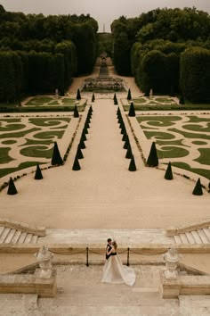 the bride and groom are standing in front of an elaborately designed garden with steps leading up to it