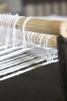 a close up view of a weaving machine with white yarn on the loomse