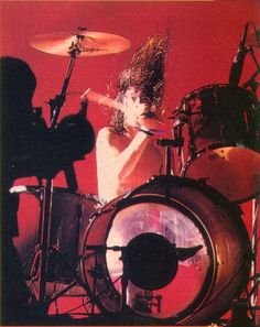 a man with long hair playing drums on stage