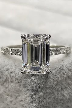 an emerald - cut diamond ring sits on top of a furry surface