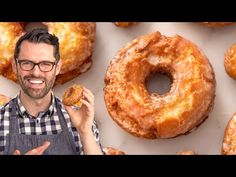 a man holding a donut in front of a bunch of doughnuts