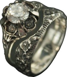 a silver ring with a diamond in the center and an intricate design on it's side