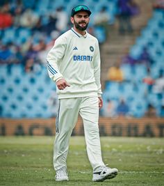 a man standing on top of a field wearing white pants and a green cap with the word daecin written on it