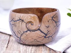 a wooden bowl sitting on top of a table next to a white napkin and green plant