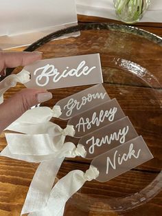 the bride and groom name tags are being held by someone's hand on a table