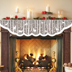 two people sitting on a couch in front of a fire place with candles and christmas decorations