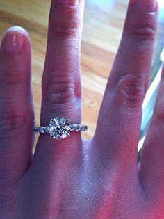 a close up of a person's hand with a diamond ring on their finger