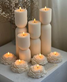 white candles are arranged on a table with flowers