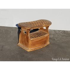 a wooden foot stool sitting on top of a cement floor