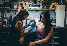 two women in a room with tattoos on their arms