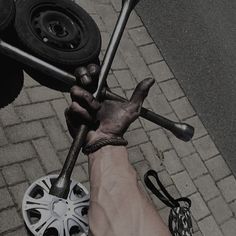 a person holding two wrenches in their hand on the ground next to a tire