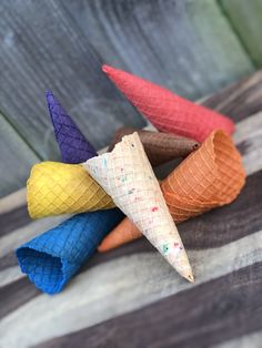 four ice cream cones with sprinkles in them on a striped cloth surface