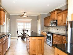 a large kitchen with wooden cabinets and black counter tops, along with a dining room table