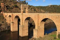 an old stone bridge spanning the width of a river