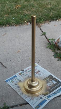 a newspaper laying on the ground next to a metal pole with a magazine in it